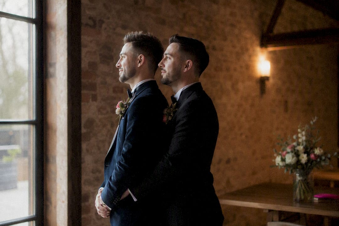 Two grooms in a dim barn wedding venue