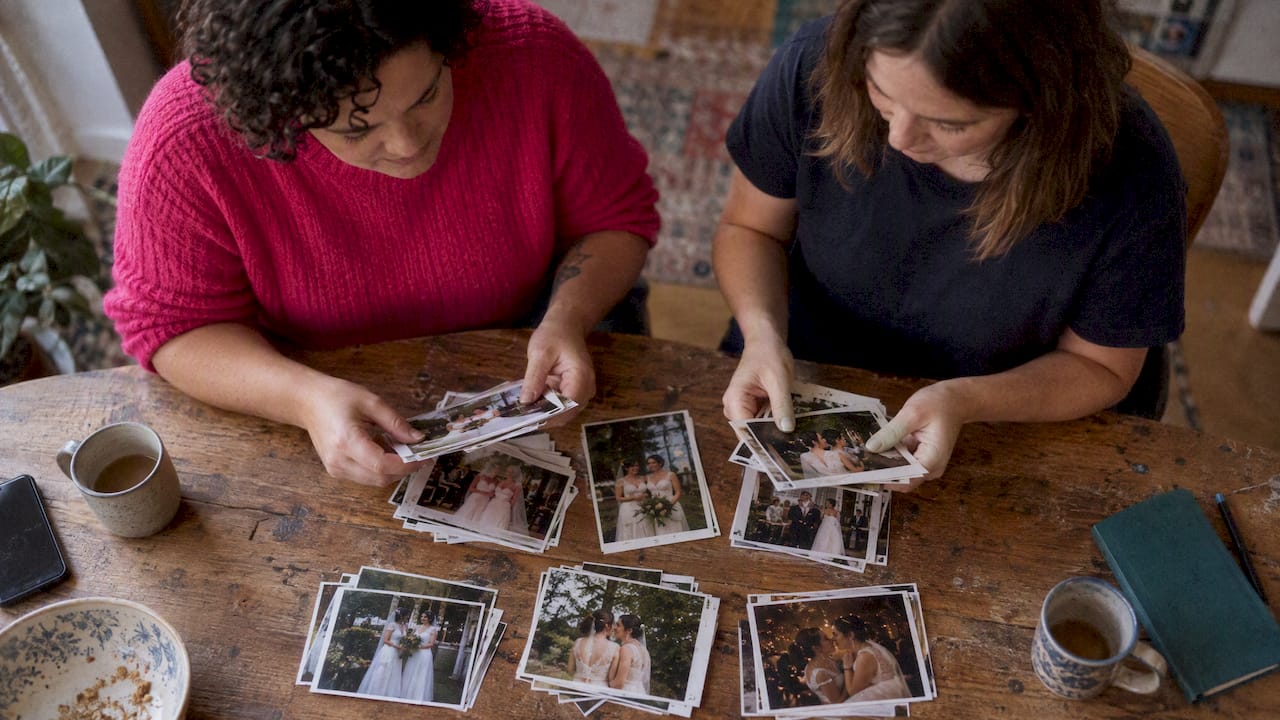 Two women counting their wedding photo prints