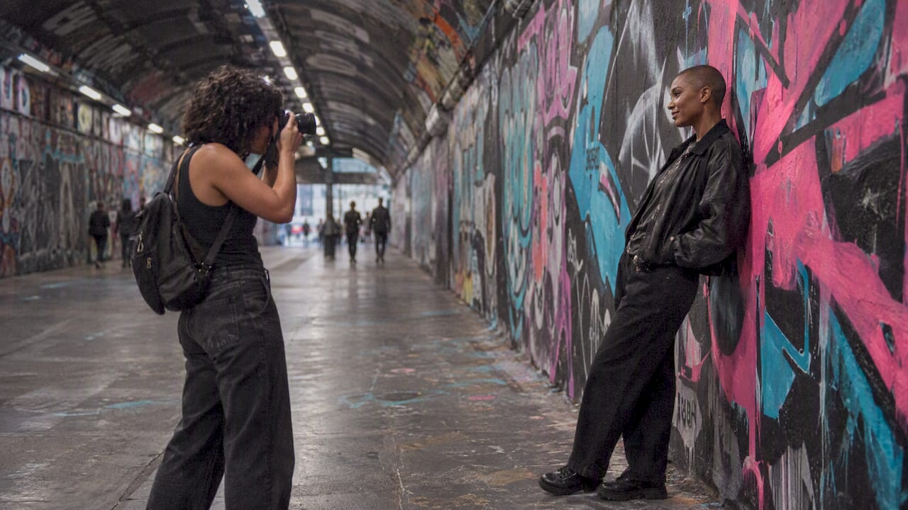 Two women photographing a portrait in a graffiti tunnel