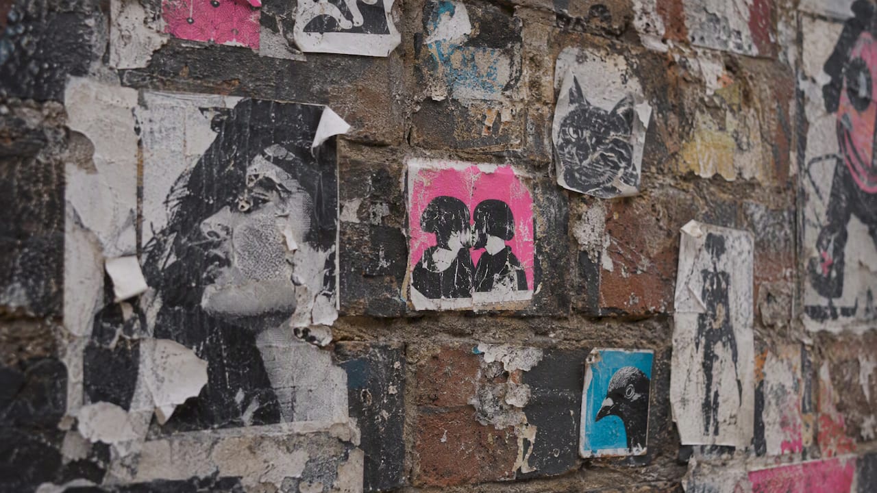 Layered stickers and wheat-paste on a Brick Lane wall